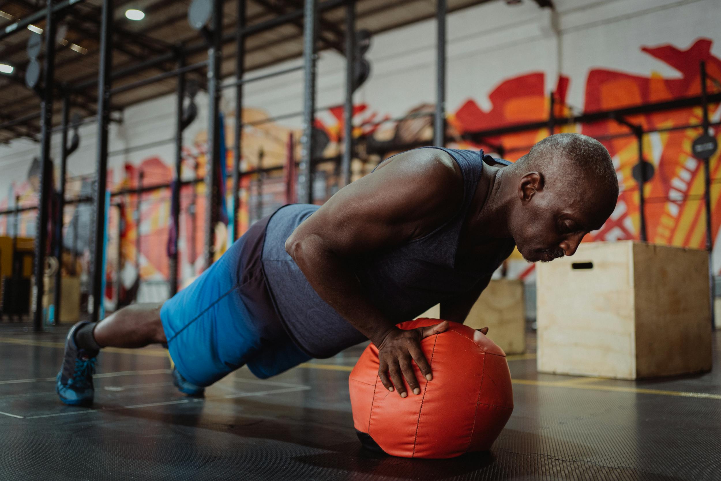 man in gym doing incline push up on a workout ball