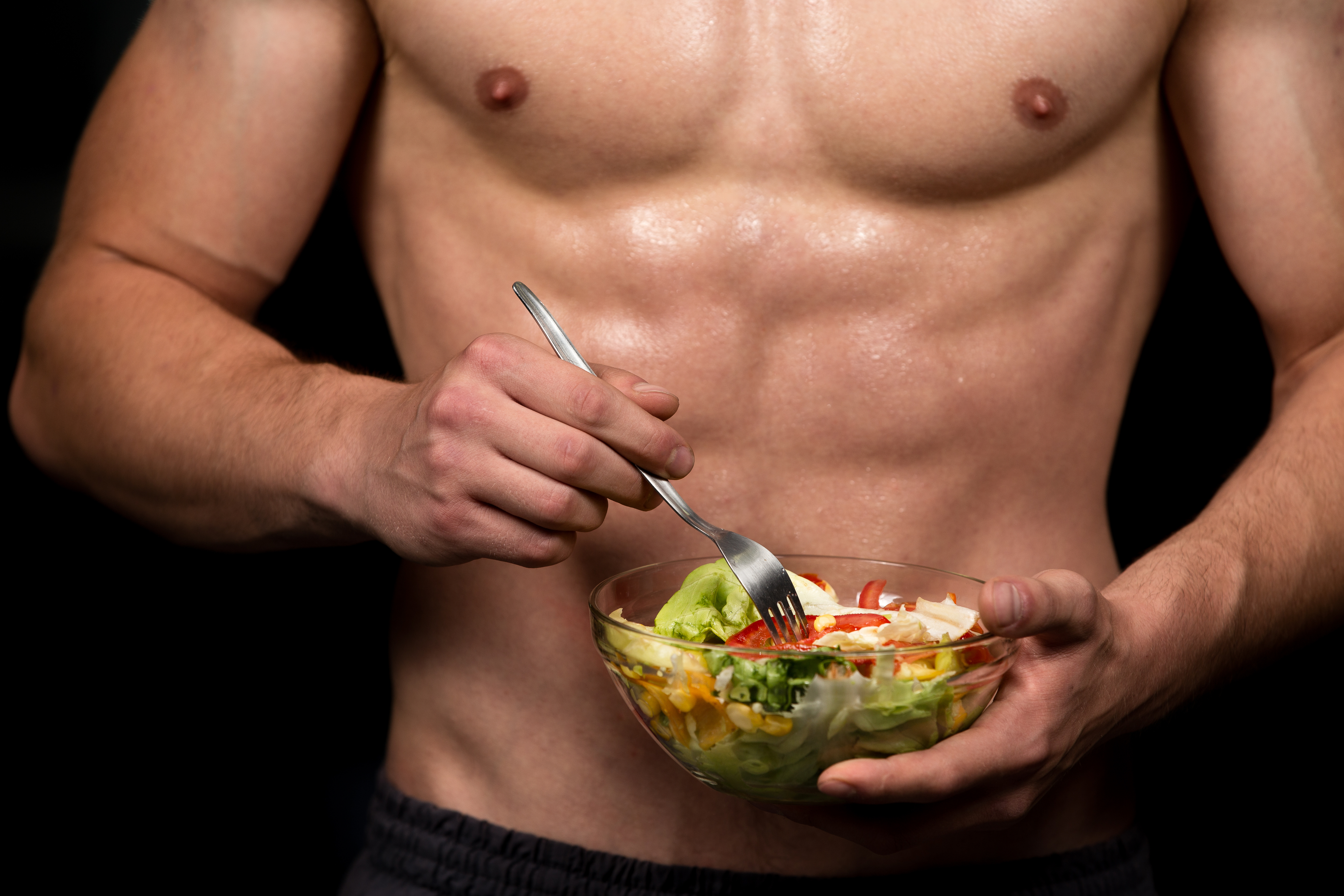 Shaped and healthy body building man holding a fresh salad bowl