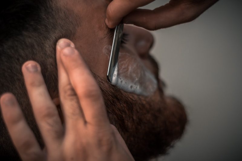 A man getting his beard trimmed