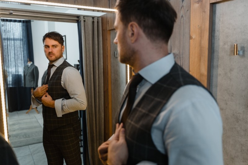 A man in a suit looking in a mirror